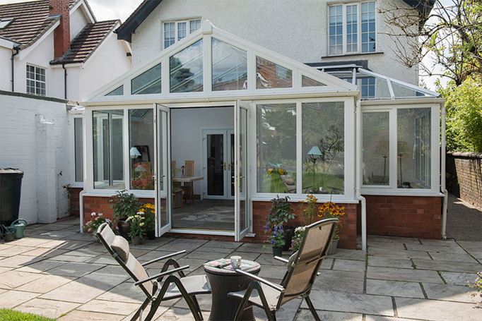 White uPVC T Shaped Harmony conservatory with French doors and tilt and turn windows in open positio