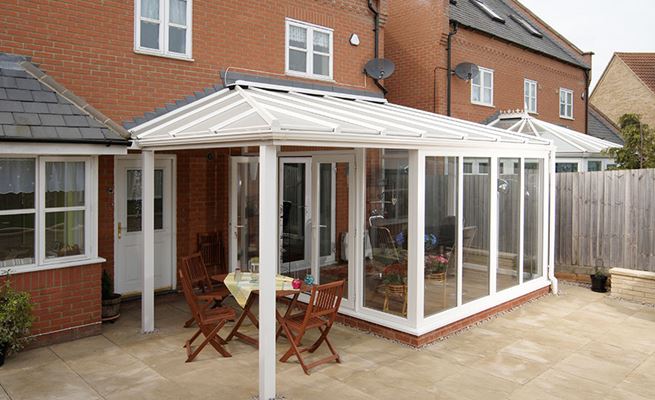 White UPVC garden room Veranda conservatory with large casement windows and French doors open onto patio 