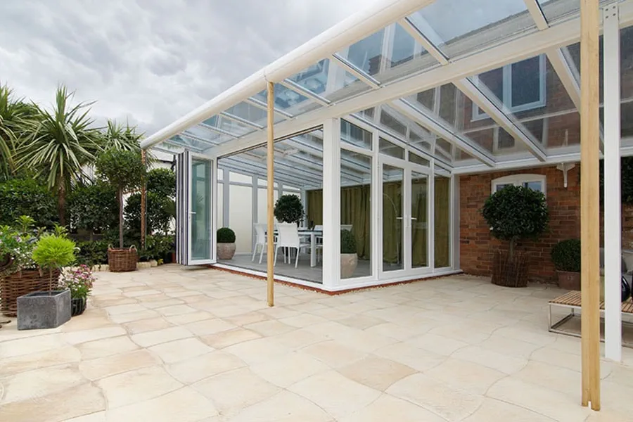 White UPVC Veranda conservatory with large bi-fold doors on side and French doors onto large patio from Anglian Home Improvements