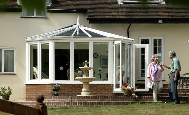 Victorian style UPVC conservatory in white with French doors opening onto patio from the Anglian classic conservatory range