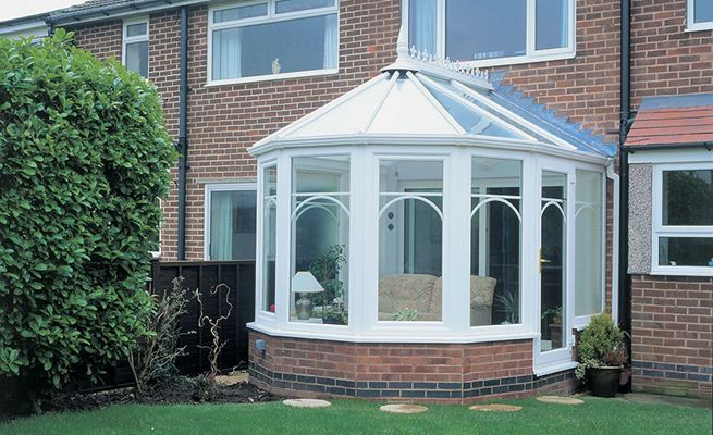 White UPVC Victorian style conservatory with single glazed back door and casement windows with curved Georgian window bars