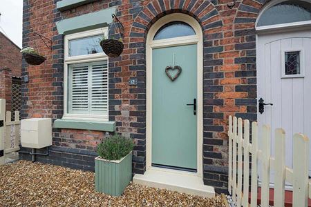 Eyebrow shaped window above sage green front door