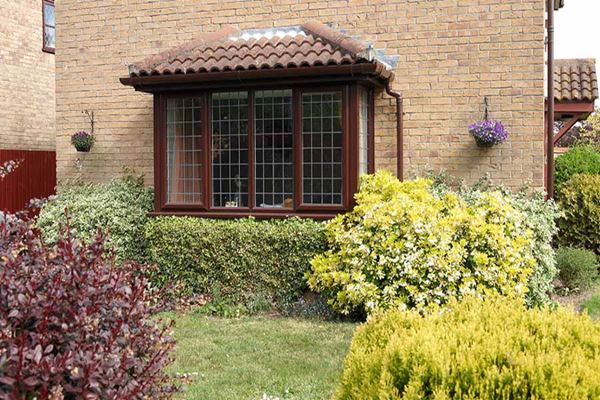 Double glazed UPVC bay window finished in Dark Woodgrain and leaded bar glass from the Anglian UPVC windows range