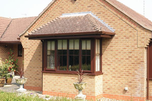 Dark Brown woodgrain UPVC bay casement window with Georgian bars on brick bungalow from the Anglian double glazing range