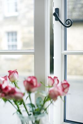 Close up of White timber cottage casement window with decorative monkeytail window handle