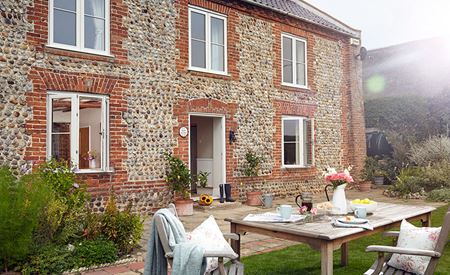 Detached property featuring timber windows & door viewed from the garden