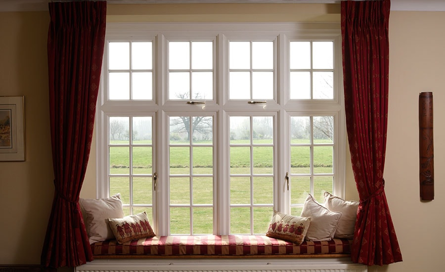 Large White timber casement window with cottage bars finished with a window seat from the Anglian double glazing range