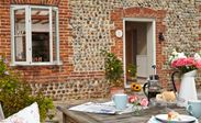 Patio view of White wooden double glazed casement window on cobblestone house from Anglian Home Improvements