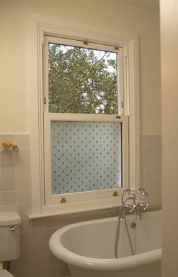 White wooden sash bathroom window with etched glass effect and gold window furniture