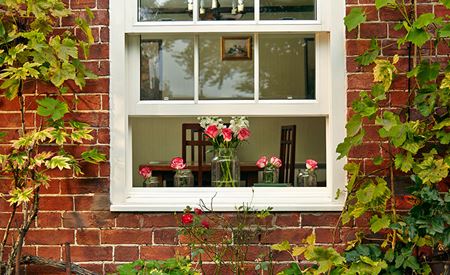 White timber sliding sash window with red flowers on the windowsill