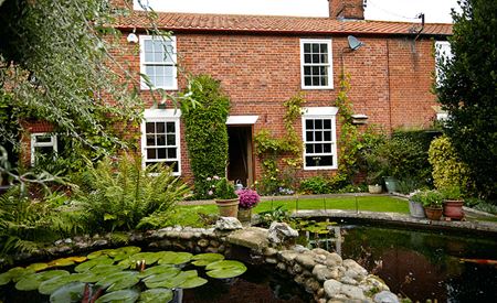 Detached property featuring timber sliding sash windows and pond in foreground
