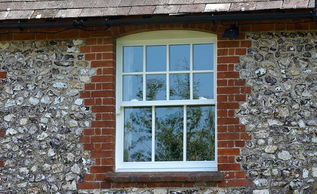 White wooden sliding sash window with cottage bars on first floor of traditional home