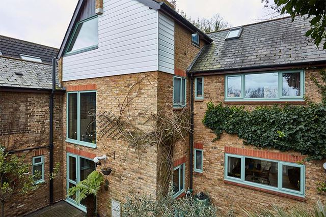 Sage green Raked Head uPVC shaped window on whole house