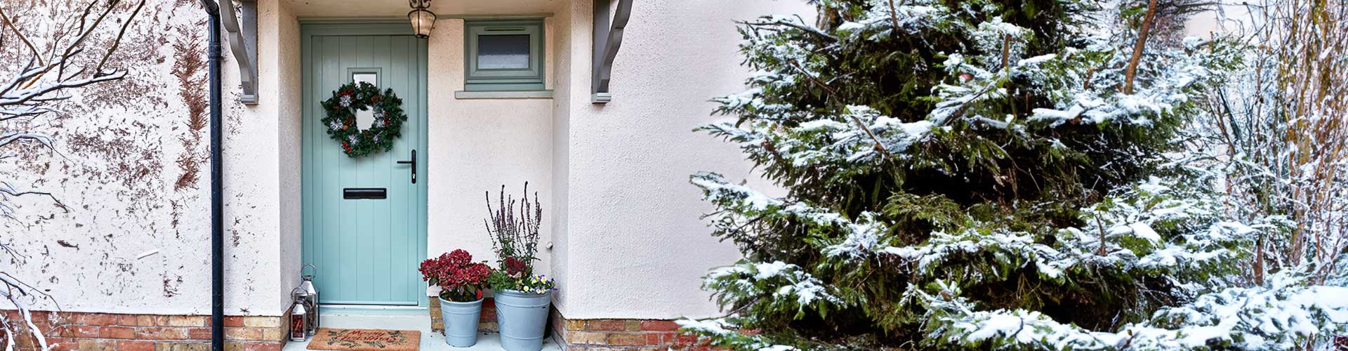 Composite door banner with a snowy tree and wreath on the door