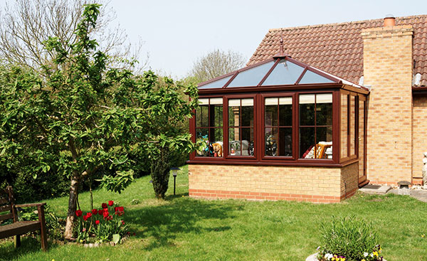 Large dark woodgrain uPVC conservatory with decorative finial from Anglian Home Improvements